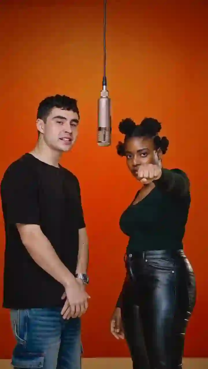 A frame from a Hotel Lobby video: two people in an orange booth with a microphone between them